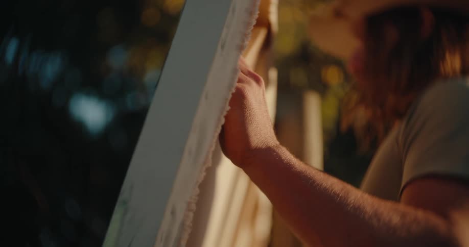 Man wearing a hat works on a wooden structure outdoors
