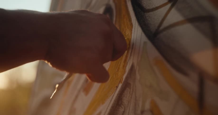 Hand applies yellow brushstrokes on a canvas during painting