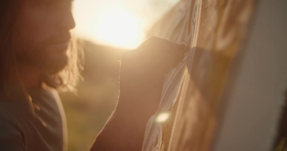 Man painting outdoors during sunset focused on his artwork under soft golden light
