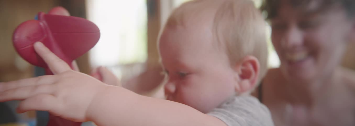 Mother smiling beside daughter reaching out toward the left side