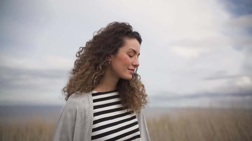 Woman smiling as she stands under a cloudy sky