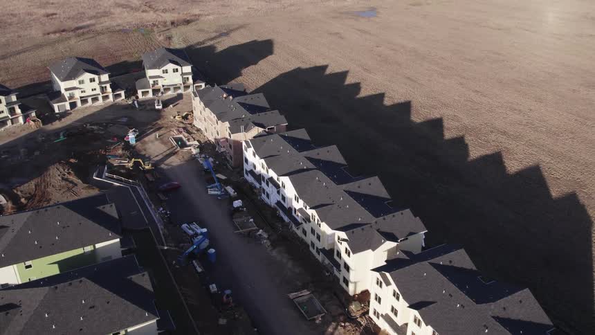 Highangle aerial view slowly moving forward and to the right over a residential area showing a continuous line of attached structures under construction