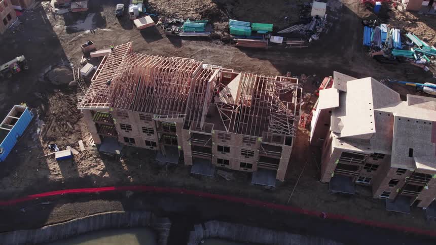 Aerial view of a construction site with workers building apartment structures