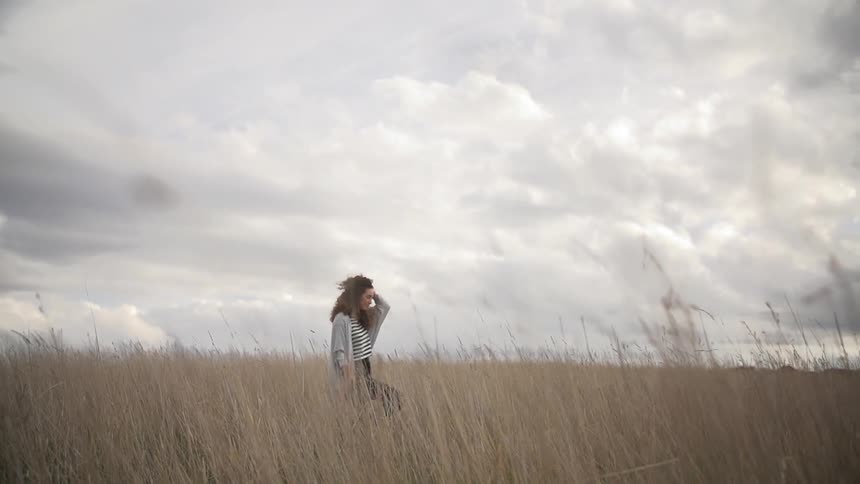 Woman standing in a field on a cloudy day
