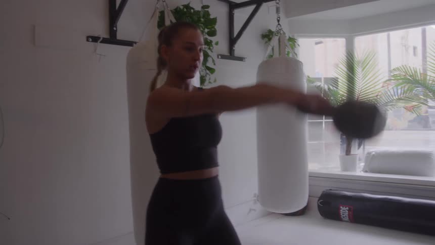 The woman is working out in the gym with a kettle bell