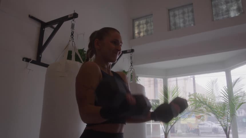 Woman exercises in a boutique boxing gym with a view of the street