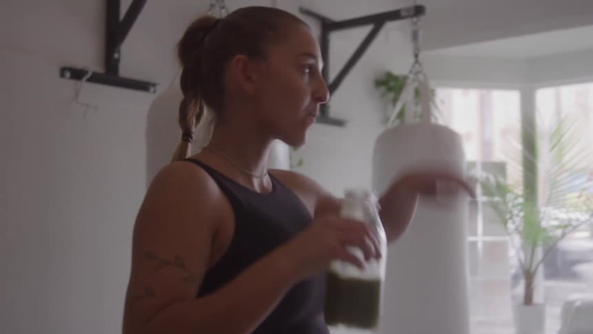 Woman drinking a green juice in a workout space