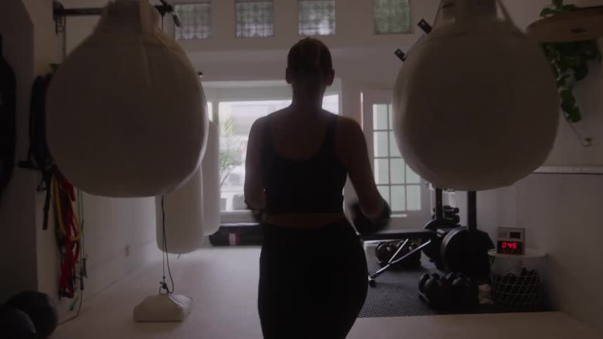 The woman walks over and punches the heavy bag
