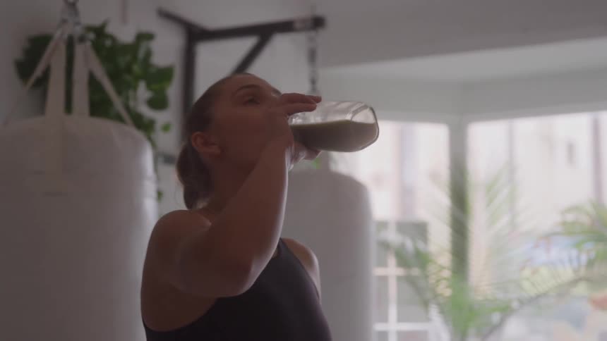 A woman drinks a refreshing green smoothie in a modern gym