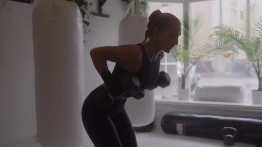 A woman in workout attire is performing weighted rows in a gym