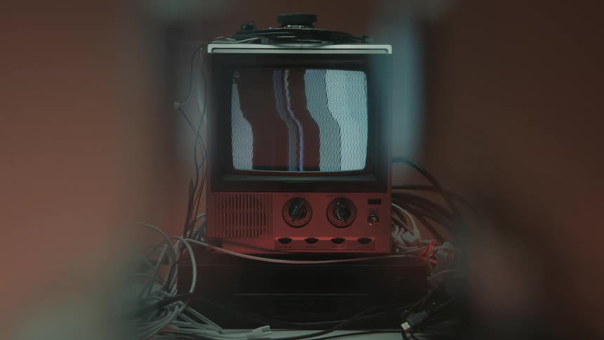 Old television displays static amid tangled cables