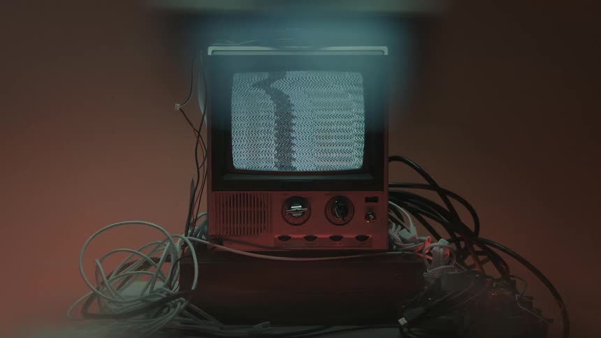 Old television displays static noise under a bluish beam of light