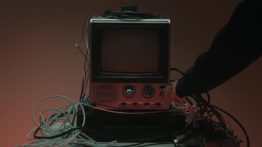 Man turns off a small television surrounded by computer cables