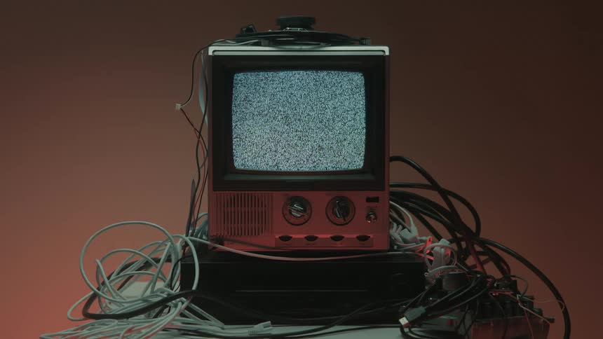 Old television surrounded by cables with no signal