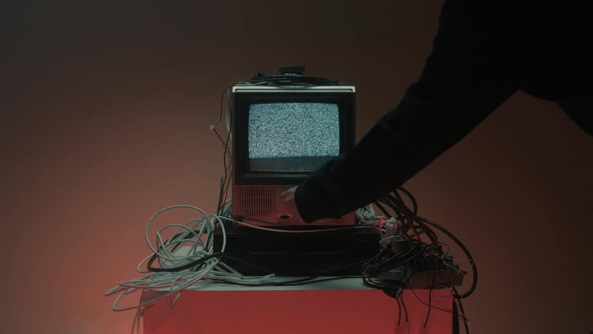 Person turning the knob on an old television with no signal