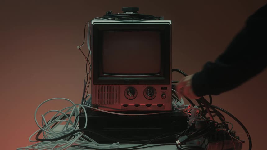 Man turns off a small television surrounded by computer cables