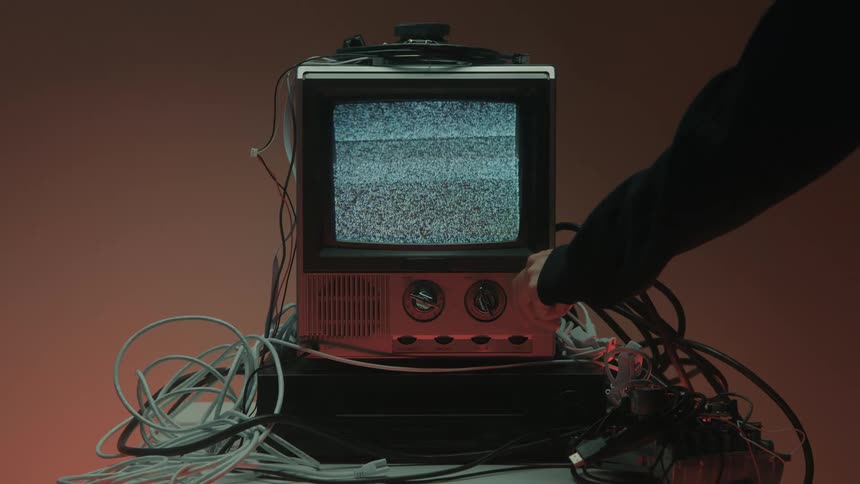 Close up of a person turning off a connected electronic display device on a table in a red lit room