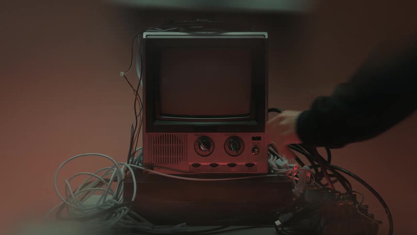 Close up of a person turning off a connected electronic display device arranged on a table in a red lit room