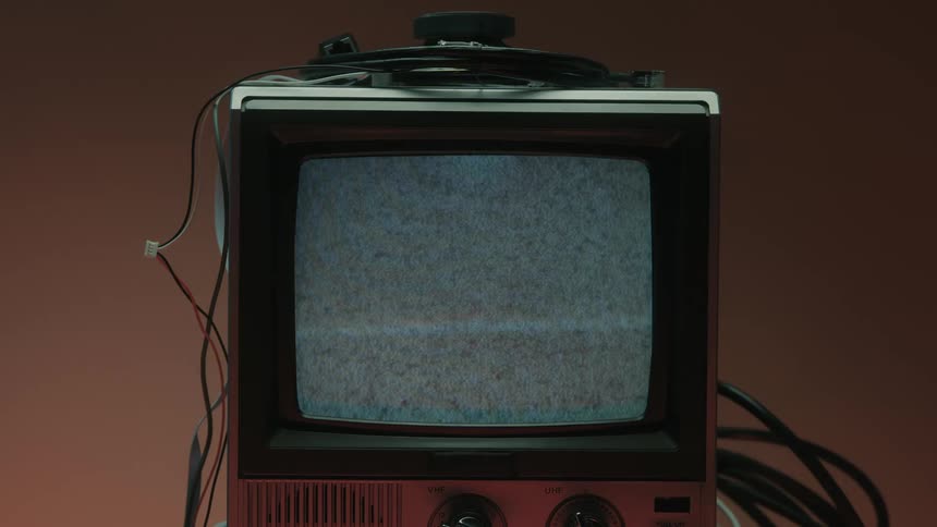 Finger pressing a button and turning on an old television with no signal