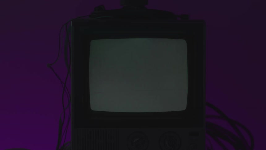 Small television in an area lit by colored lighting displays a series of symbols