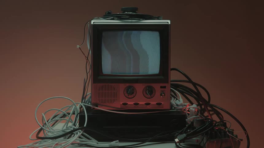 Hand turns a knob while powering on an old television with the screen off