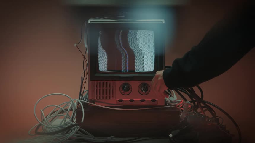 Person reaching over to shut off a static filled television