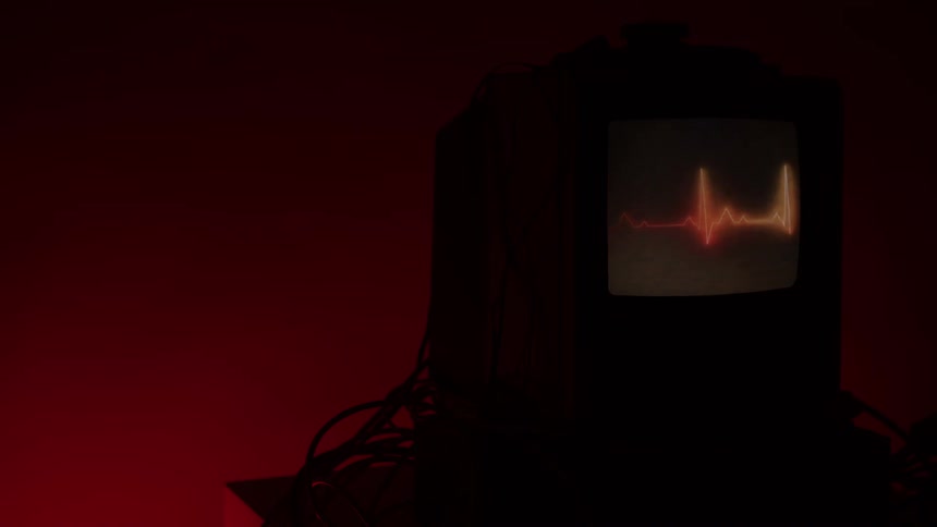 Closeup of monitor displays glowing cardiac waveform on screen