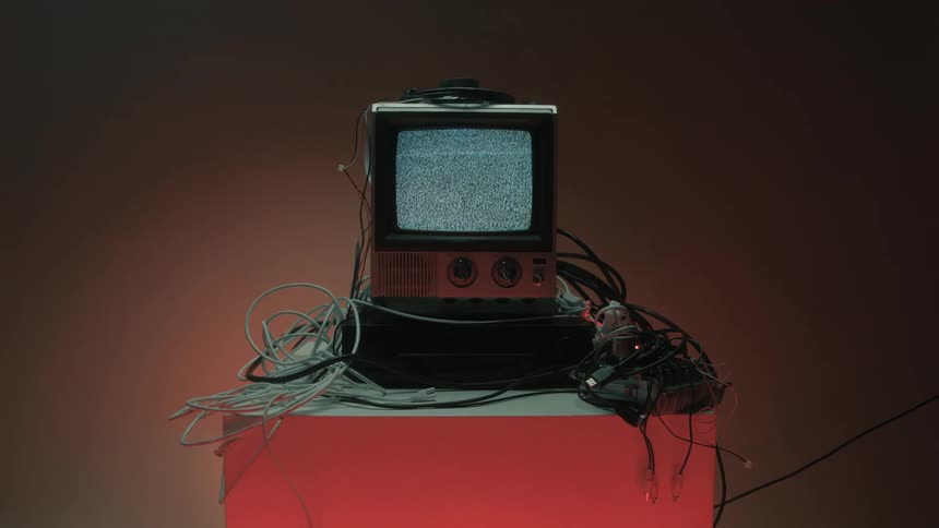 A television set displaying a distorted vertical pattern of visual noise surrounded by loose cables
