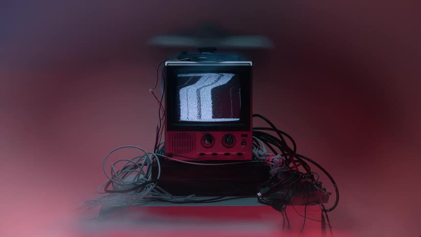 A television set displaying a distorted vertical pattern of visual noise surrounded by loose cables