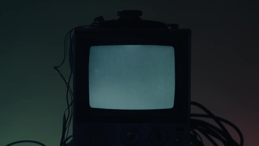 An older model television monitor with a continuously illuminated white screen in an indoor setting