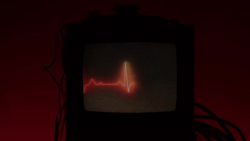 Person turns on an old monitor displaying a red heartbeat line