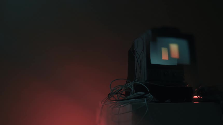Symbols flash on the small television in the dark room