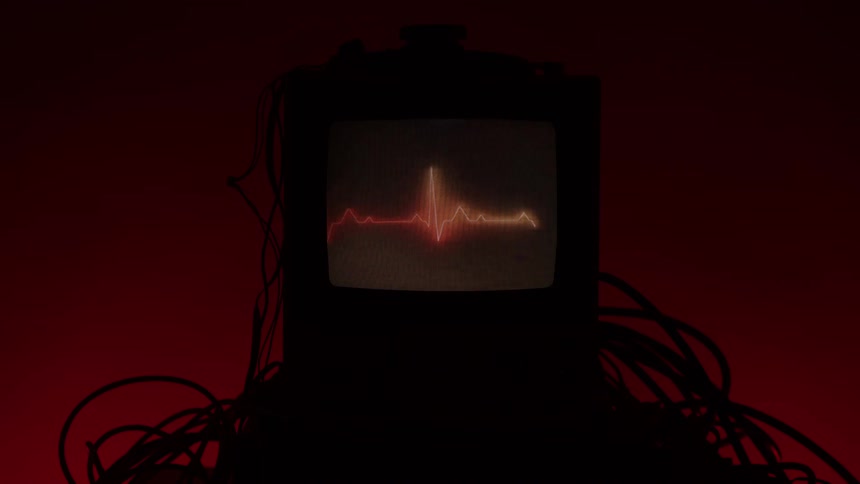 Old monitor displaying a heartbeat line with cables around it