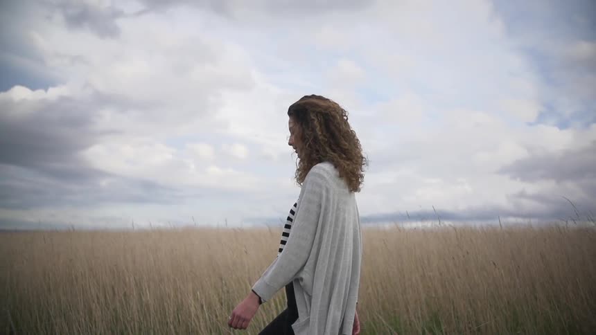 A woman walking through a field on a cloudy day