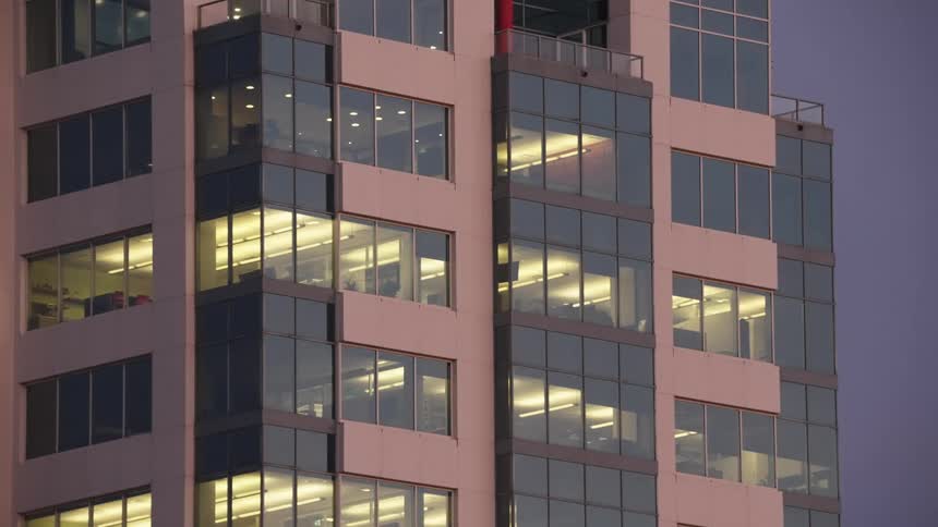 Interior lights illuminate the floors of a corporate building at dusk