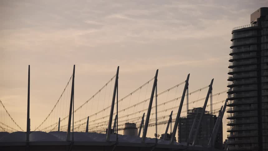 The top of a highrise building in the city silhouetted against the warm glow of the sunset