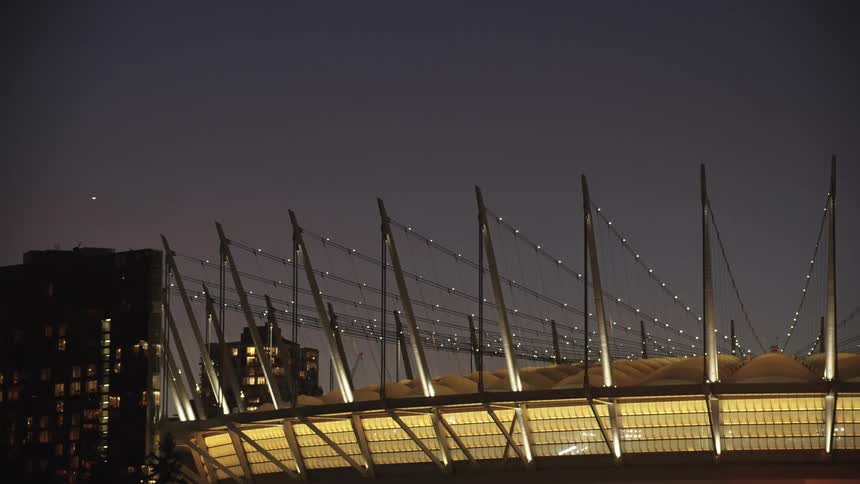 Bc place stadium glows at night in vancouver with white masts standing out against the dark sky and lit buildings in the background