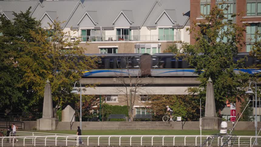 Train in motion passing through an urban area with people walking below