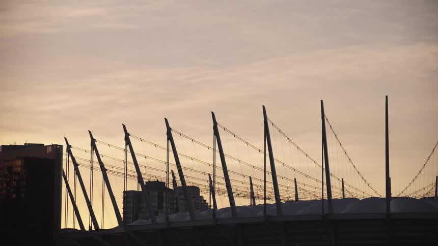 Modern structure with cables and masts stands out against the sky at sunset