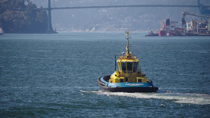 The tugboat travels in the water towards the bridge