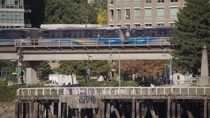 The train passes by as people walk and ride bikes