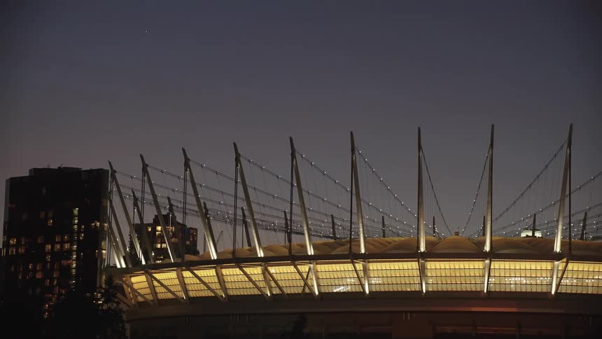 Stadium illuminated at night with prominent cables and metal structures