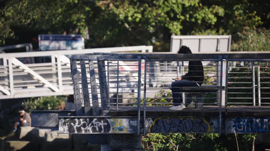 Person sitting on a graffiticovered bridge using a phone