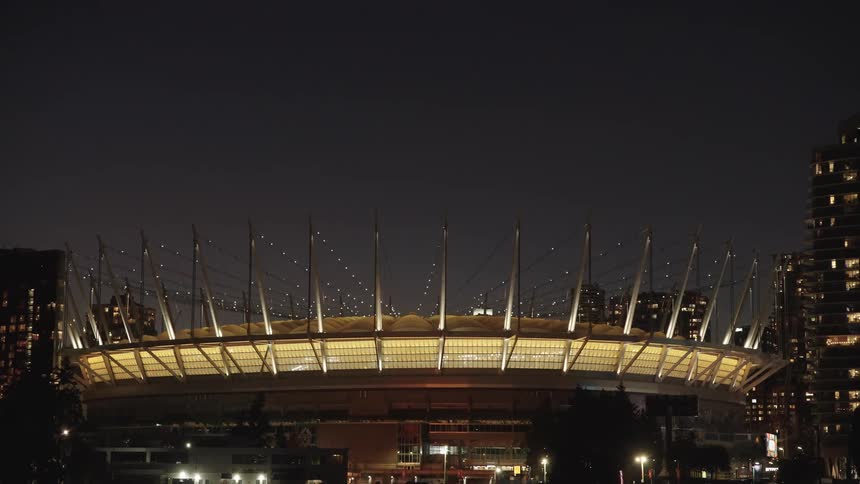 Domed stadium with spires lit up in city skyline at night