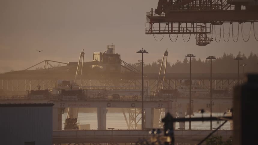 Industrial structures stand out at sunset near the port