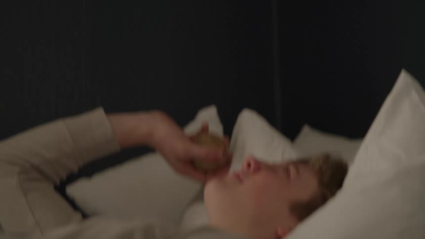 Man lying down on bed tossing baseball up in the air