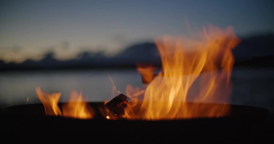 A person runs up to a campfire where there is a marshmallow roasting on a stick