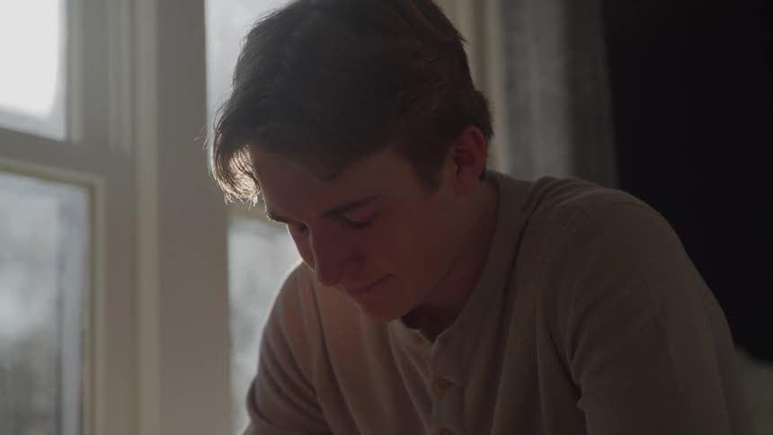 The teenager looks sad by the window