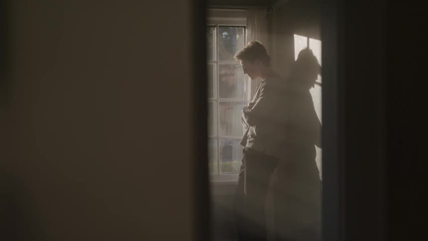 The teenager is looking out the window