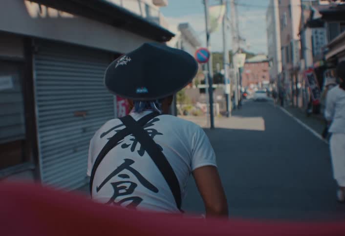 From a passengers pov a rickshaw puller sways left and right dodging pedestrians while navigating a narrow japanese street